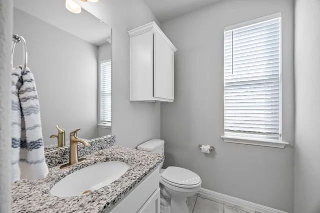 a bathroom with a granite countertop sink toilet and mirror