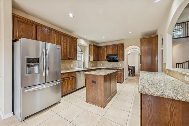 a kitchen with stainless steel appliances granite countertop a refrigerator stove top oven and sink
