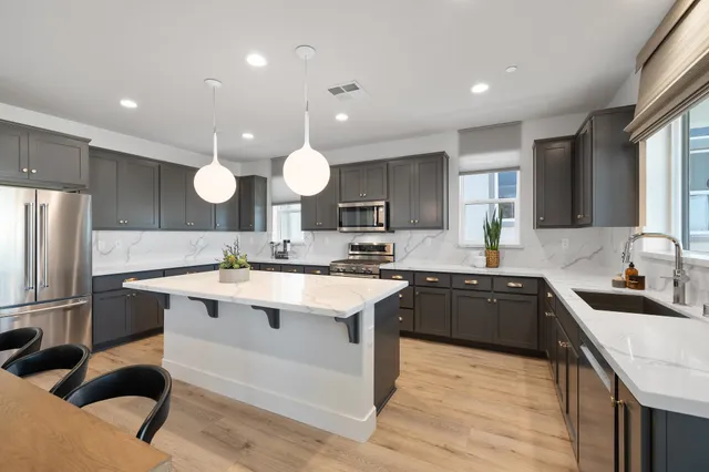 a large kitchen with a sink a center island stainless steel appliances and cabinets