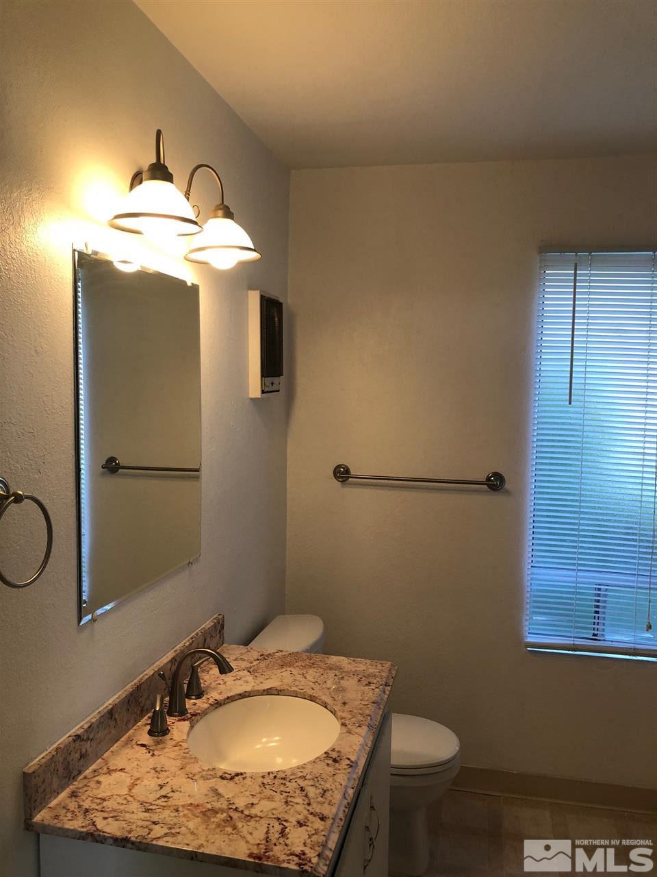 3942 Clear Acre Lane Reno, NV 89512 - Photo 17 of 24 a bathroom with a granite countertop sink toilet and mirror
