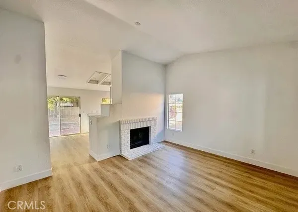 a view of empty room with wooden floor and fireplace
