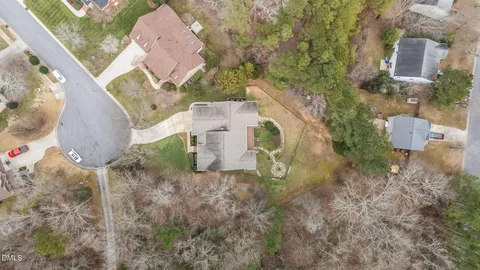 an aerial view of a house with yard and trees all around