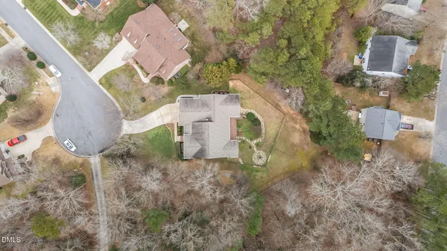 an aerial view of a house with yard and trees all around