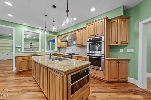 a kitchen with stainless steel appliances granite countertop a sink a stove and a wooden floors