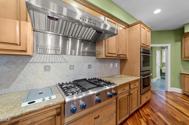 a kitchen with stainless steel appliances granite countertop a stove a sink dishwasher and a refrigerator with wooden floor