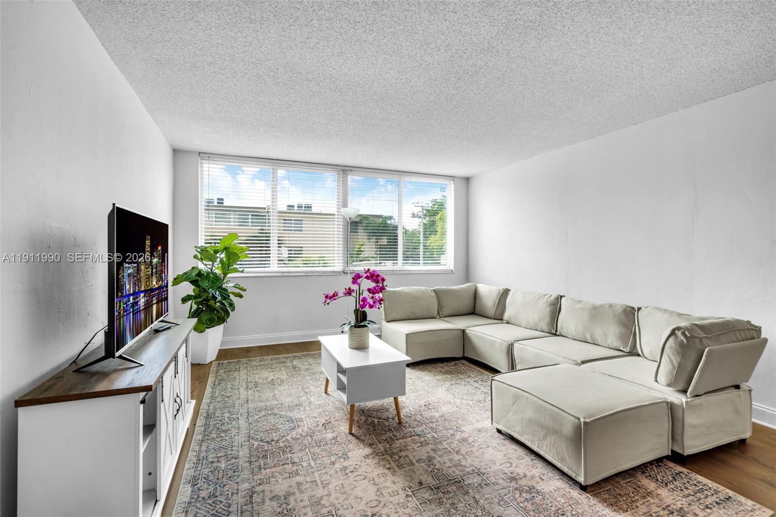 9125 Southwest 77th Avenue, Unit 202 Miami, FL 33156 - Photo 3 of 30 a living room with furniture a flat screen tv and a large window