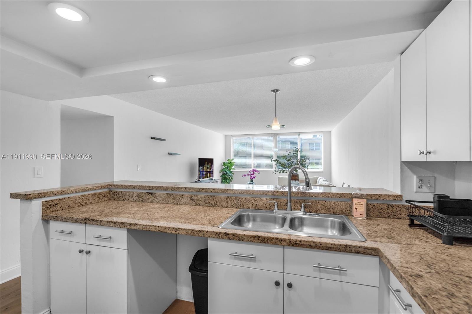 9125 Southwest 77th Avenue, Unit 202 Miami, FL 33156 - Photo 8 of 30 a kitchen with granite countertop a sink and white cabinets