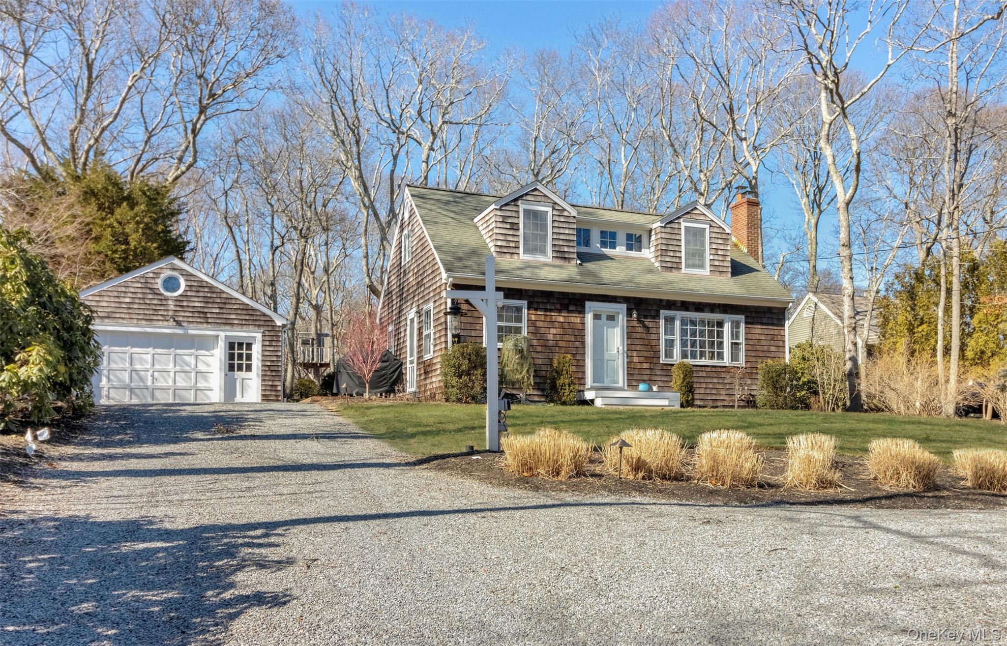 1500 Vanston Road Cutchogue, NY 11935 - Photo 13 of 26 View of front facade featuring an outbuilding, gravel driveway, a detached garage, a chimney, and a front lawn