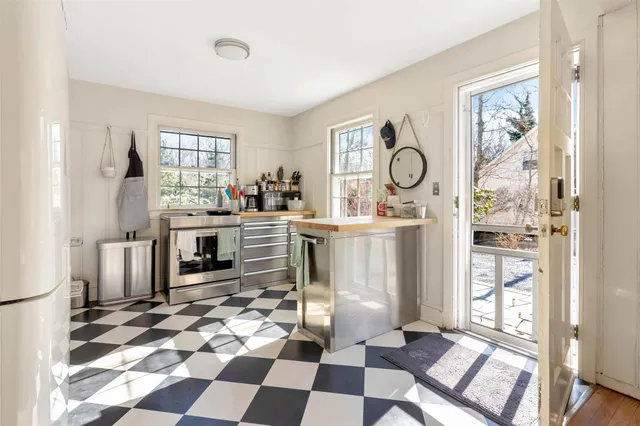 a room with a black white checkered floor with a gaming machine and dining chairs