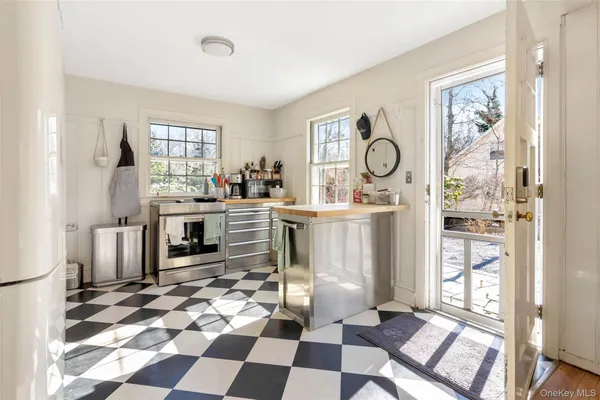 a room with a black white checkered floor with a gaming machine and dining chairs