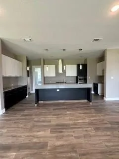 a living room with stainless steel appliances granite countertop furniture and a wooden floor