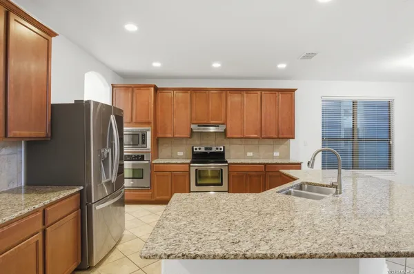 a large kitchen with stainless steel appliances granite countertop a stove refrigerator sink and cabinets