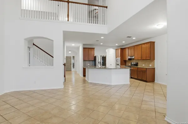 a view of kitchen with kitchen island granite countertop a stove a sink a refrigerator and white cabinets