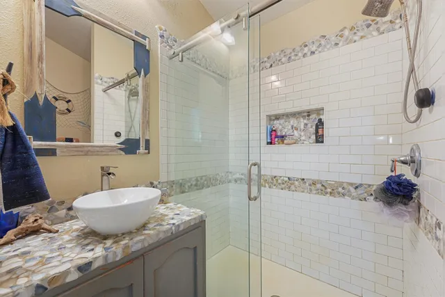 a bathroom with a granite countertop sink a mirror and shower