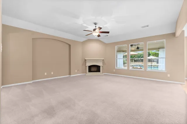 an empty room with fireplace fan and windows