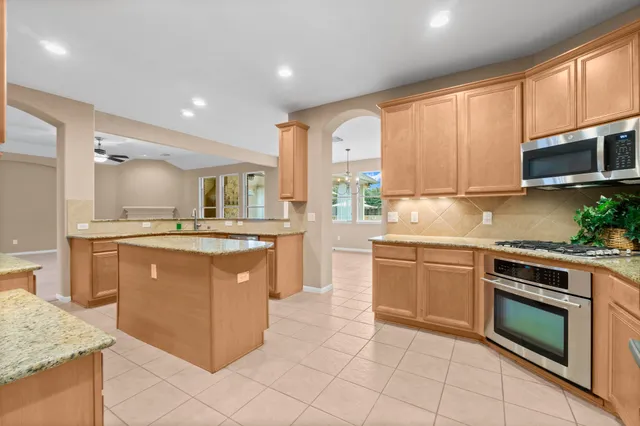 a kitchen with stainless steel appliances granite countertop a stove a sink and a microwave