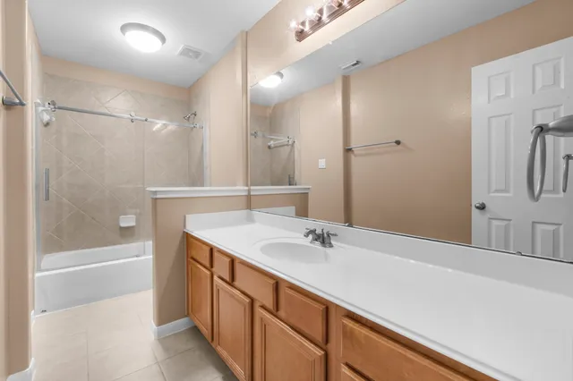 a bathroom with a tub sink shower and two mirror