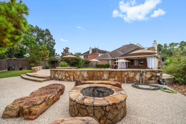 a view of a patio with couches and a fire pit and wooden fence
