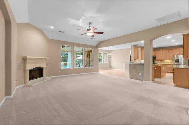 a view of an empty room with a fireplace and a kitchen view