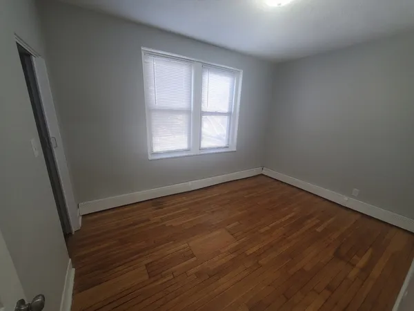 an empty room with wooden floor and window