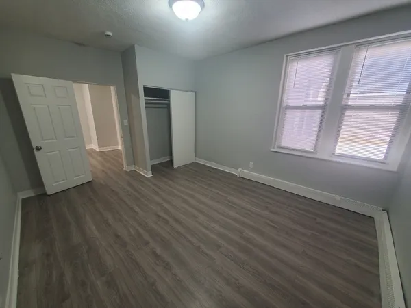 an empty room with wooden floor and windows