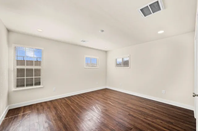 an empty room with wooden floor and windows