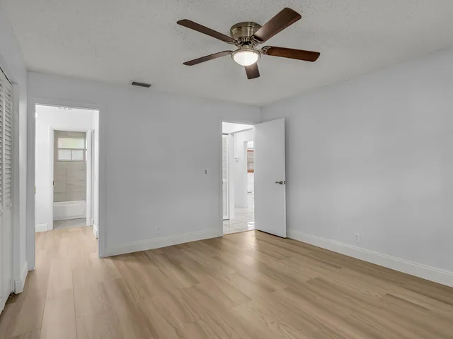 an empty room with wooden floor and a ceiling fan