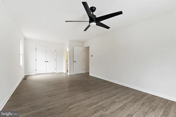 an empty room with wooden floor cabinet and windows