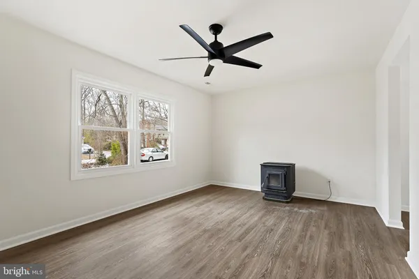 a view of empty room with wooden floor and ceiling fan