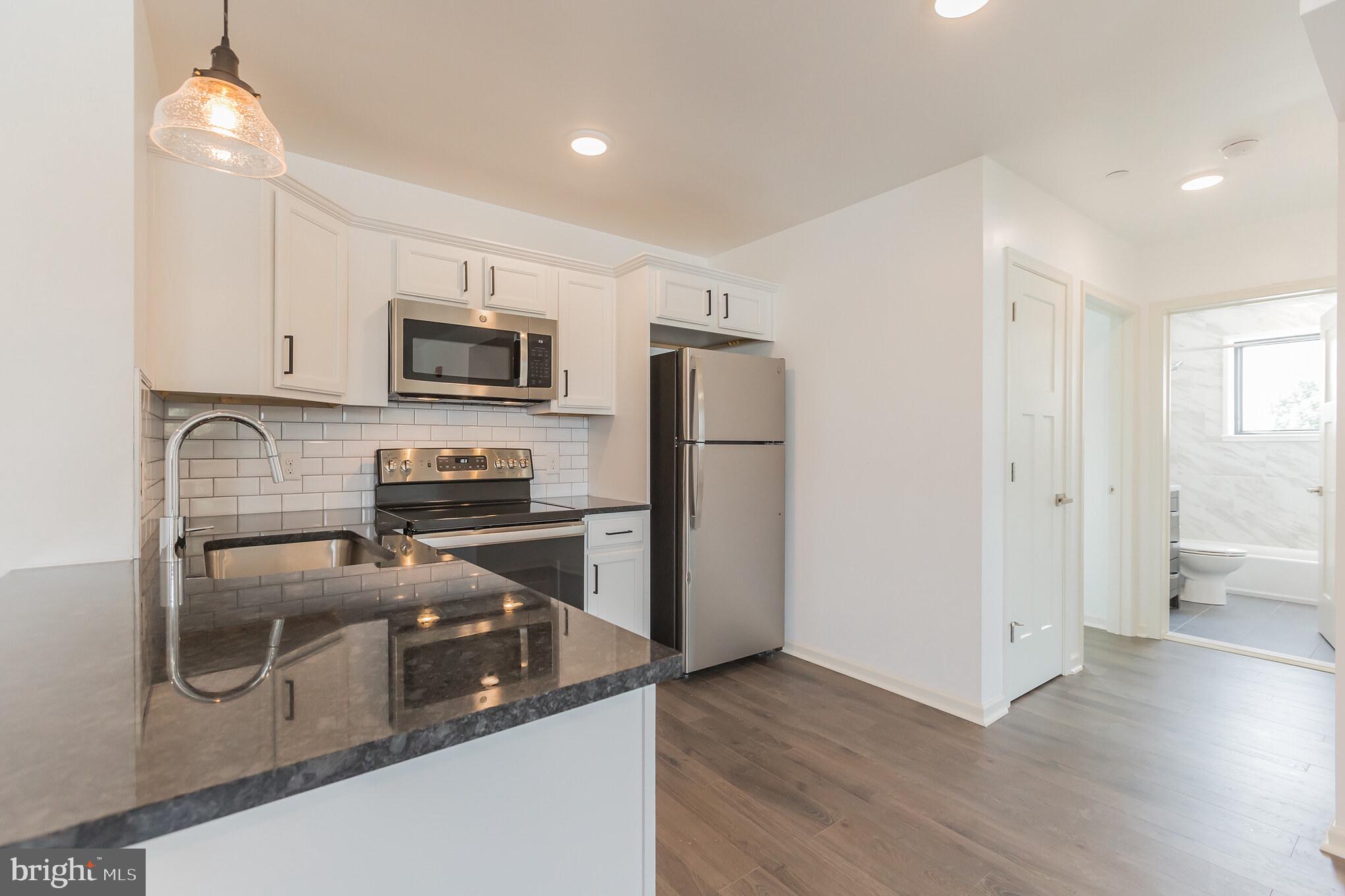 6778 Ridge Avenue, Unit 201 Philadelphia, PA 19128 - Photo 2 of 15 a kitchen with a refrigerator microwave and stove top oven