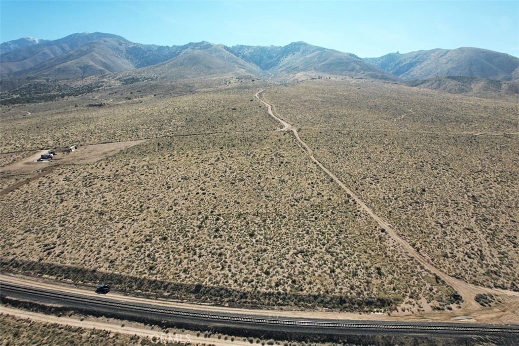 39 Santa Rosa Road Lucerne Valley, CA 92356 - Photo 7 of 18 a view of a dry yard with mountain and trees
