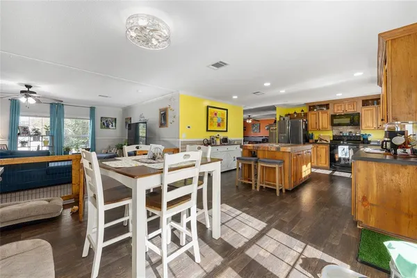 a kitchen with stainless steel appliances granite countertop a refrigerator a sink dishwasher a stove and a dining table with wooden floor