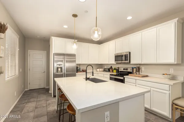 a kitchen with a sink a stove a refrigerator and white cabinets