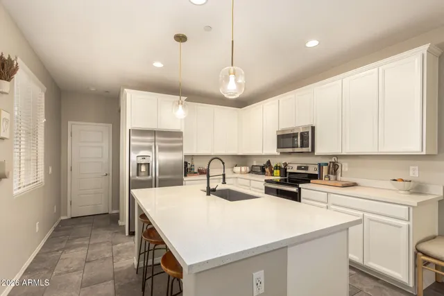 a kitchen with a sink a stove a refrigerator and white cabinets