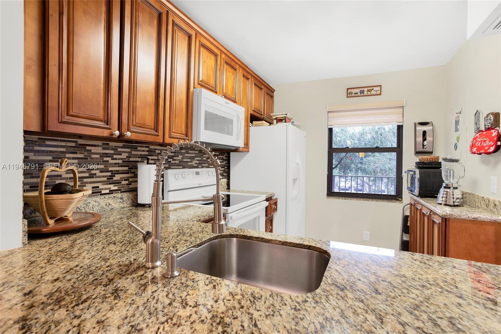 2941 North Nob Hill Road, Unit 208 Sunrise, FL 33322 - Photo 21 of 40 a kitchen with kitchen island granite countertop a sink a counter top space and cabinets