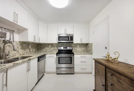 a kitchen with granite countertop white cabinets and a stove