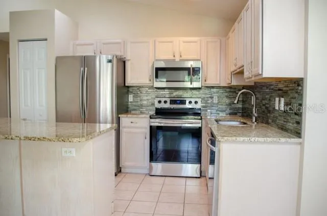 a kitchen with stainless steel appliances granite countertop a sink a stove a refrigerator a microwave and cabinets
