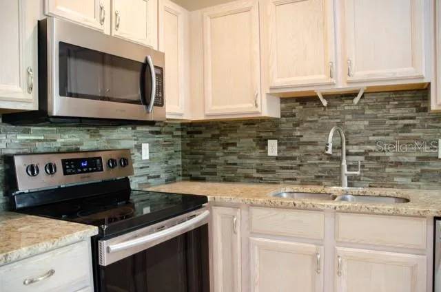 a kitchen with granite countertop a stove sink and microwave