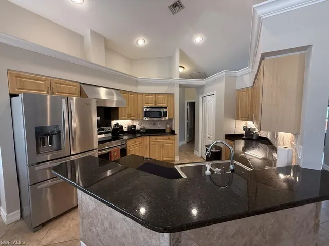 a kitchen with stainless steel appliances granite countertop a sink a stove and a refrigerator