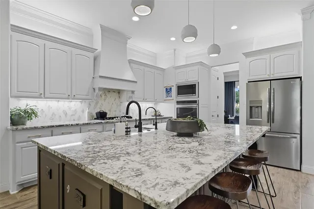 a kitchen with granite countertop a table chairs stove and refrigerator