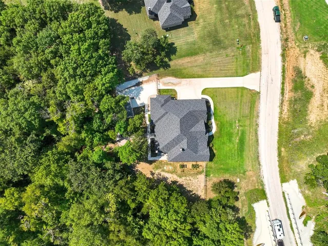 an aerial view of a house with a yard lake and trees all around