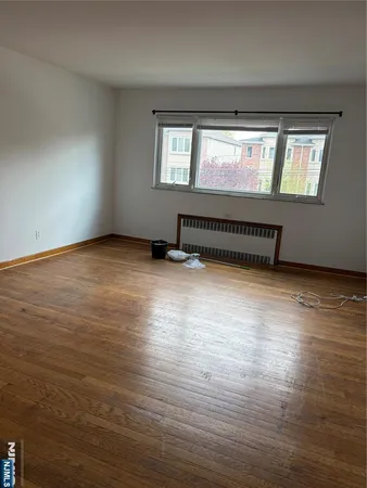 a view of an empty room with wooden floor and windows