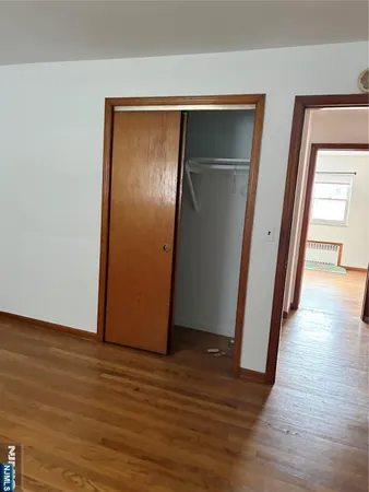 a view of an empty room with wooden floor and closet