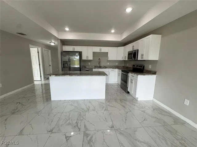 a view of kitchen with stainless steel appliances granite countertop a stove top oven a sink a microwave and a refrigerator