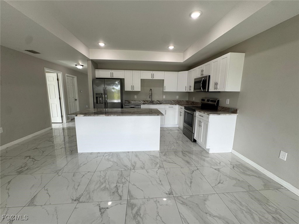 610 Alabama Road South Lehigh Acres, FL 33974 - Photo 3 of 12 a view of kitchen with stainless steel appliances granite countertop a stove top oven a sink a microwave and a refrigerator