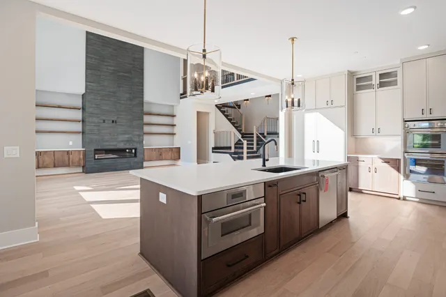 a kitchen with stainless steel appliances granite countertop a sink a stove and a wooden floors