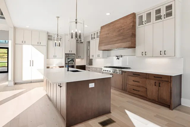 a kitchen with stainless steel appliances kitchen island granite countertop a sink a stove and a refrigerator