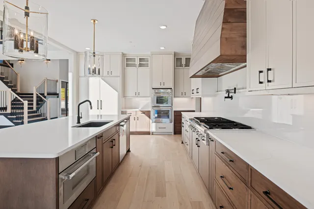 a kitchen with stainless steel appliances granite countertop a sink a stove and a wooden floors