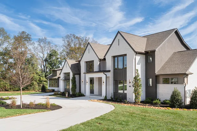 a view of a white house with a big yard and large tree