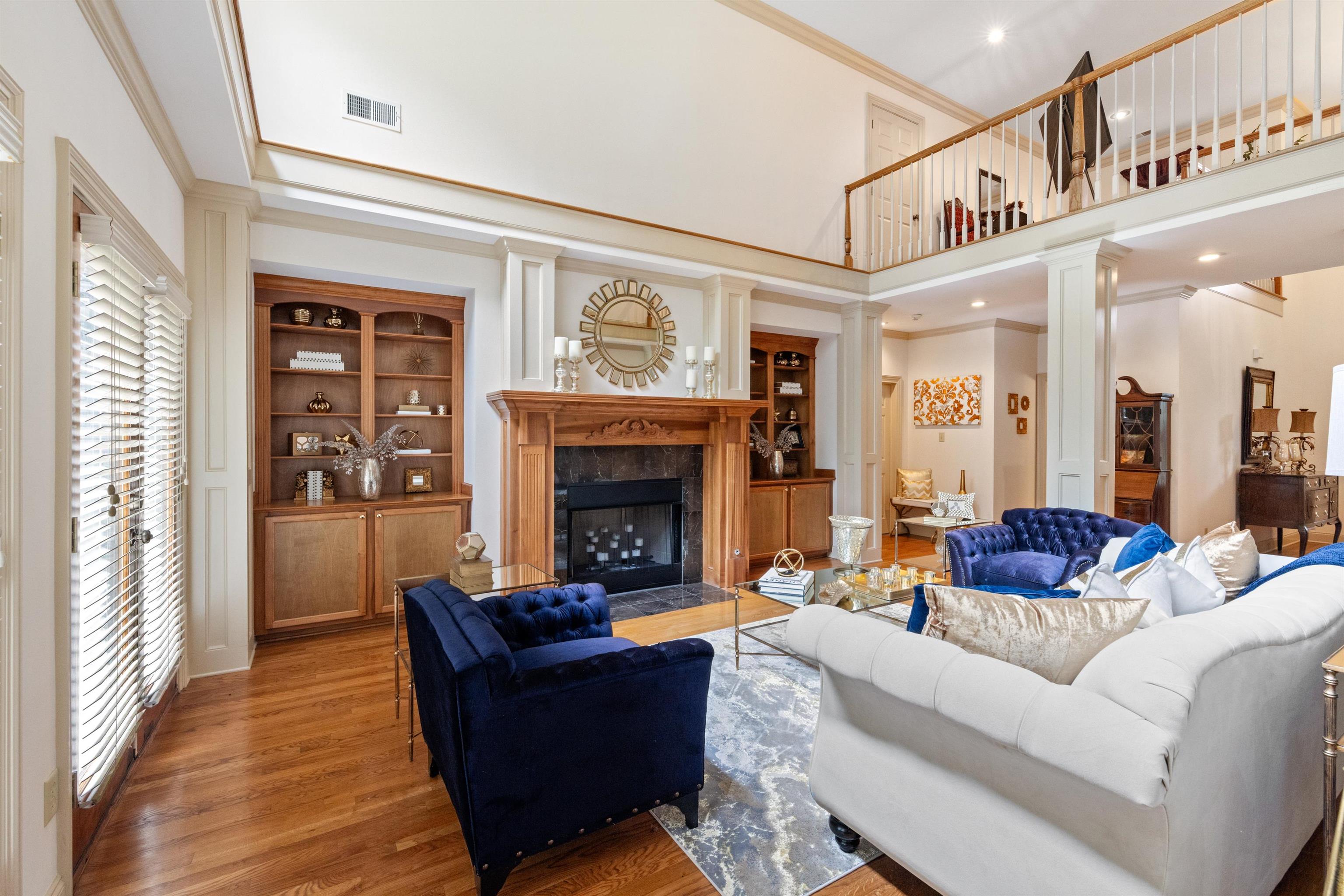 11241 Latting Road Eads, TN 38028 - Photo 12 of 31 Living room featuring a towering ceiling, wood-type flooring, decorative columns, a fireplace, and crown molding